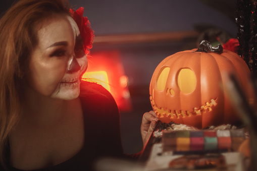 Close up of a woman applying skull makeup for Halloween or Mexican Day of Death celebration,Halloween costume,Halloween holiday concept.