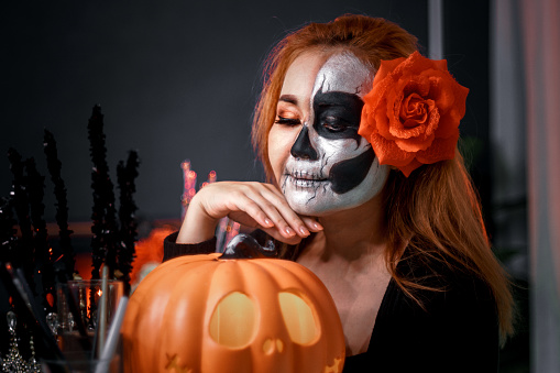 Close up of a woman applying skull makeup for Halloween or Mexican Day of Death celebration,Halloween costume,Halloween holiday concept.