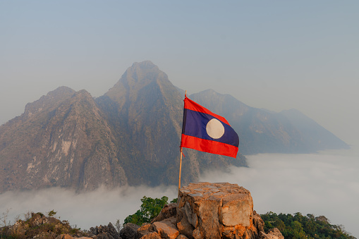 Laotian flag on top the mountain covered with fog in the morning