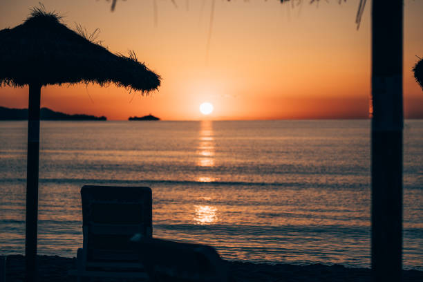 istock Sunset over the ocean with beach chairs lining the shore on a beautiful day 1970127242