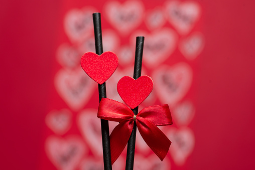 Red heart shapes on black sticks with a red bow over red background