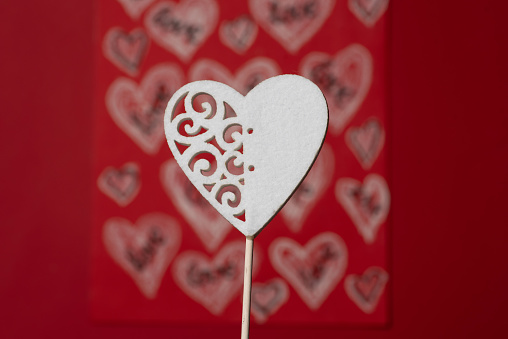 White heart shape on stick over decorated red background