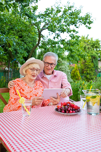 Senior couple using digital tablet while sitting at dining table in garden.