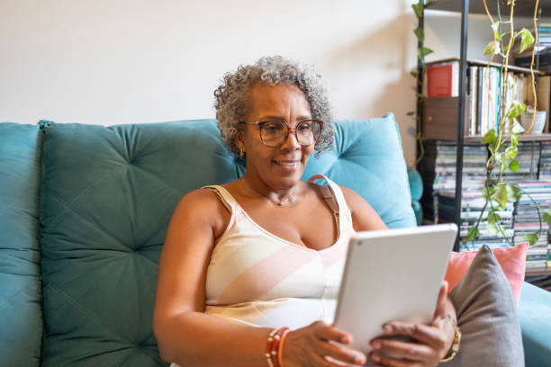 istock Middle-aged black woman using tablet in living room 1970183520