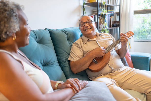 istock middle-aged latin man plays ukulele for black woman 1970185129