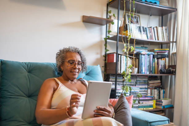 istock Middle-aged black woman using tablet in living room 1970194237