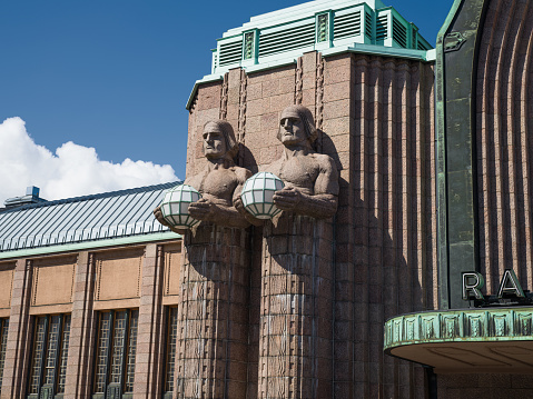 Helsinki Central Railway Station Finland Facade with Art Deco Sculptures - Lyhdynkantajat Sculptures holding copper and glass orbs at the walls of Helsinki Central Station. Monumental Art Deco statues, designed and completed in the year 1914. The Lyhdynkantajat Statues are part of the facade of the Art Nouveau Helsinki Central Station. 100 MPixel Hasselblad X2D Architecture Shot. Helsinki, Finland, Scandinavia, Northern Europe