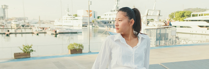 Young woman resting on the pier of the seaport, Panorama