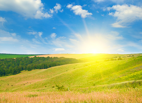 Hilly landscape, picturesque meadows and a bright sunrise.