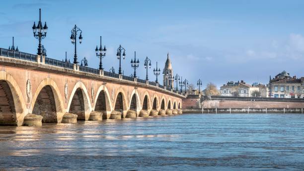istock a large stone bridge spans over the water towards a town 1970276296