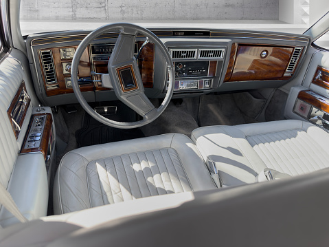 Interior detail from a classic status car with steering wheel, dashboard, and glove compartment