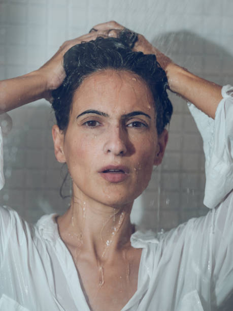 istock Wet dressed female putting hands on head in shower 1970286829