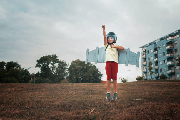 Low angle portrait of an adorable little caucasian girl being carried by her fun playful father while outside in a garden. Smiling cute daughter bonding with her dad in the backyard. Playing aeroplane