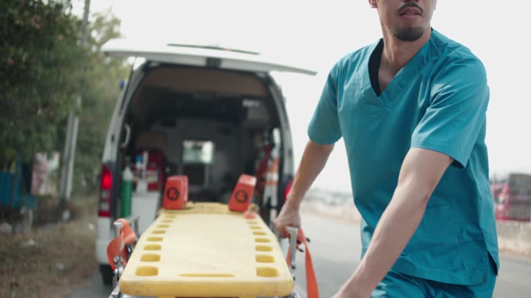 A male nurse is dragging a mobile emergency bed from an emergency vehicle