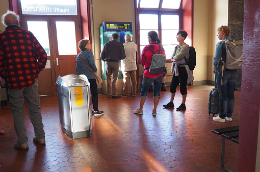 Ruedesheim, Germany – January 01, 2023: Travelers are waiting for the train in small station building, older people are taking tickets from a ticket machine, two hikers with backpacks, bus