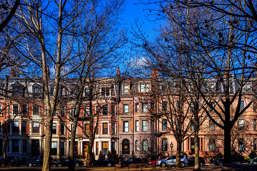 Nineteenth century brownstones on Commonwealth Avenue (aka Comm Ave). Commonwealth Avenue  is a major street in the cities of Boston and Newton, Massachusetts. It begins at the western edge of the Boston Public Garden, and continues west through the Back Bay and other neighborhoods. View across the Commonwealth Avenue Mall.