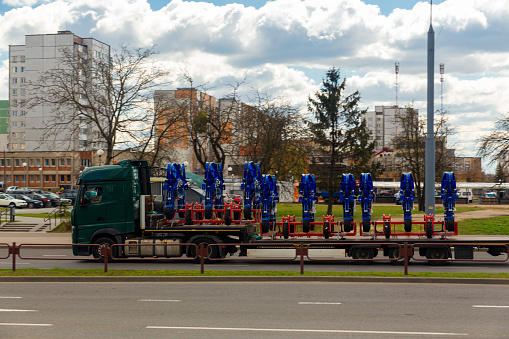 Transportation of large agro-complex machines for cultivating and sowing crops on long trailers by trucks along the street in the city