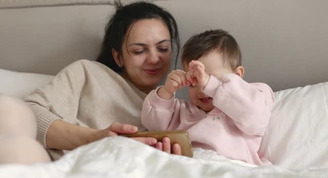 Caucasian mother and child playing online game on smartphone