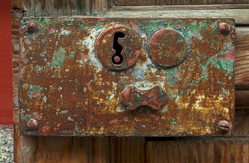 background of old rusty metal with peeling paint bordered by shiny rivets