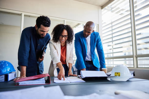 istock Smiling architects talking together over blueprints in an office 1970423531