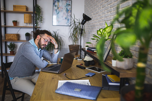 Young man tired while working late at home office