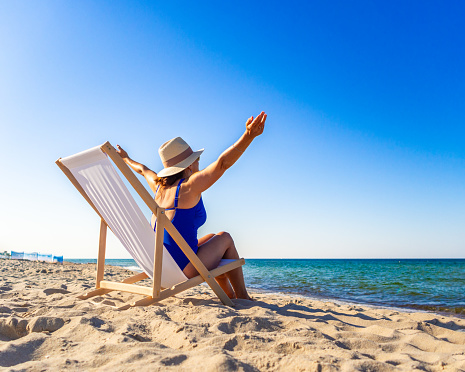 Woman relaxing on beach sitting on sunbed