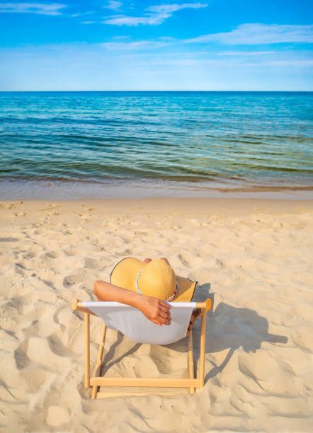 istock Woman relaxing on beach sitting on sunbed 1970438516