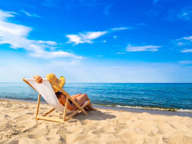 istock Woman relaxing on beach sitting on sunbed 1970439598