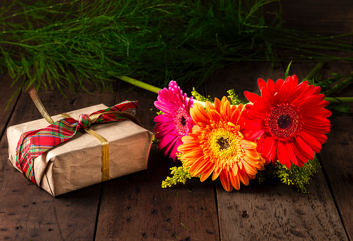 Gerbera flowers with  gift box over a rustic wooden table