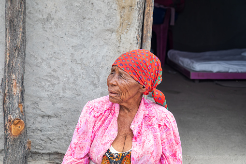 old african woman in front of her house in the village