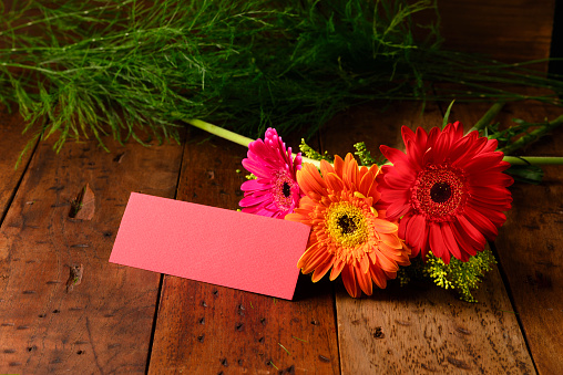 Gerbera flowers with red color label over a rustic wooden table