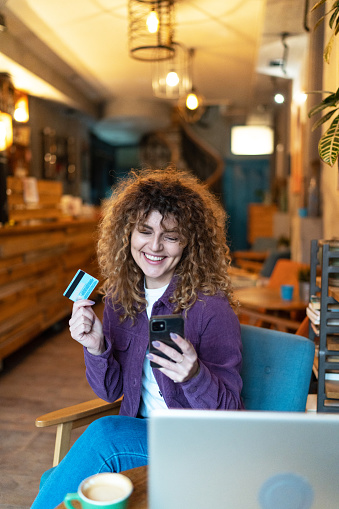 Young woman sitting at cafe making online shopping, using credit card and laptop