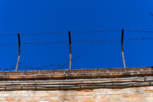 Old town of Venice with barbed wire and brick wall holocaust memorial at Ghetto Vecchio on a sunny summer day. Photo taken August 7th, 2023, Venice, Italy.