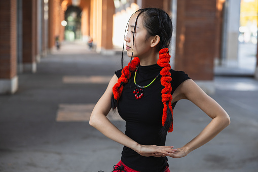 An urban dancer with a bold red scarf finds her center in a moment of calm before the performance.