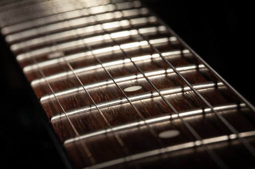low-key photo of a fragment of a black guitar against a dark background. guitar music photo aesthetic