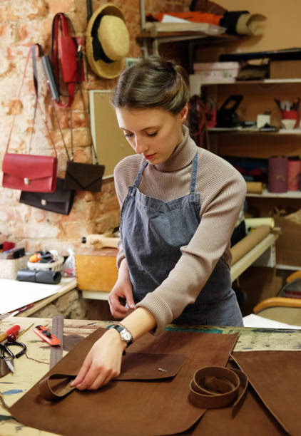 young woman works in a bag making studio, cuts out details stock photo