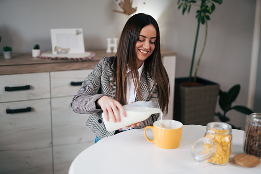 A woman pours milk for breakfast.Business woman has a healthy breakfast