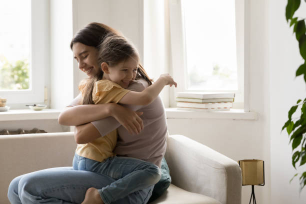 istock Mother and little daughter hugging seated on sofa 1970615027