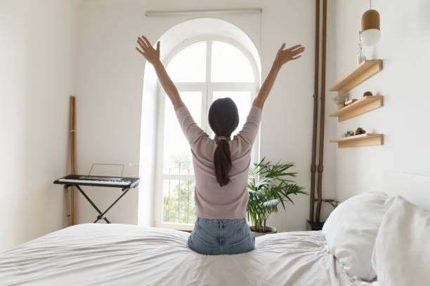 istock Dreamy young female enjoy morning sitting on bed 1970636363