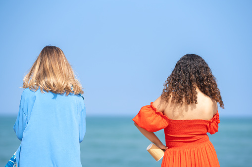 Two young women, a blonde and a brunette, on their backs looking at the sea