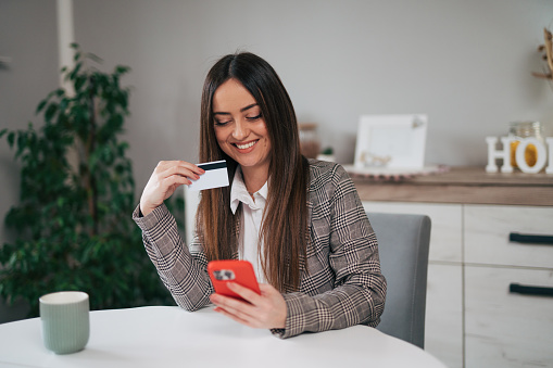 Woman holding a credit card and using smart phone for online shopping