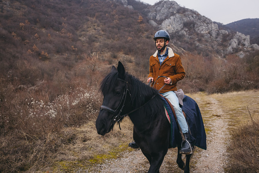 Young man riding a horse in countryside.