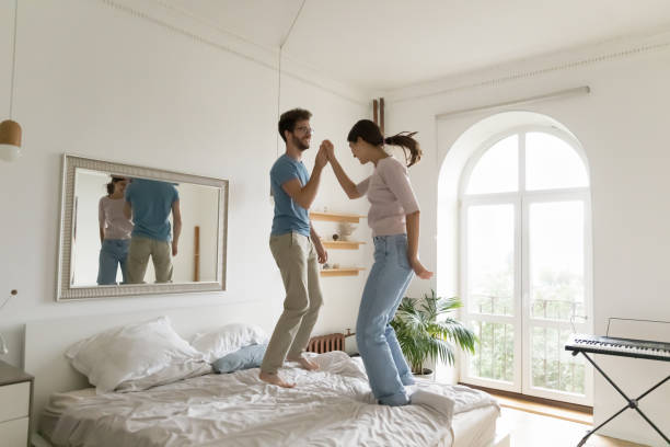 istock Funny couple jumping on bed in modern bedroom 1970652294