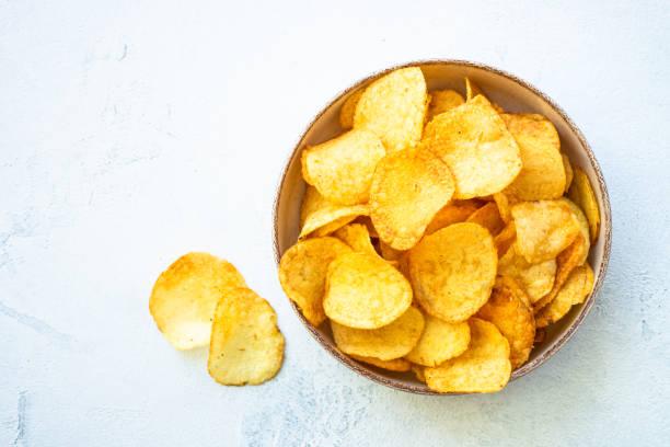 istock Potato chips in wooden bowl on white table. Top view. 1970663001