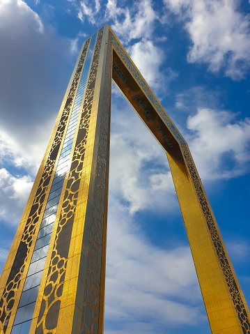 Capturing the grandeur of Dubai Frame from below, sunlight and clouds paint a mesmerizing reflection on this architectural marvel, seamlessly blending modern elegance with celestial beauty.