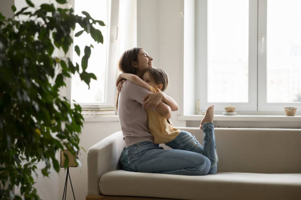 istock Mother and daughter hugging while sitting on sofa 1970705740