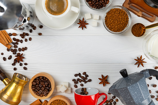 Ingredients for making coffee. Moka pot, turkish coffee pots (cezve), coffee grinder with coffee beans, milk, sugar and spices on a marble background. Drink preparation concept. Flat Lay.Copy space.