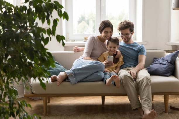 istock Joyful family spend time on sofa at home use smartphone 1970724625