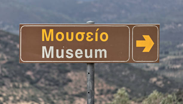 istock museum sign at archaeological site in greece (mouseio written in greek) arrow pointing (ancient mycenae historical ruin) 1970751104