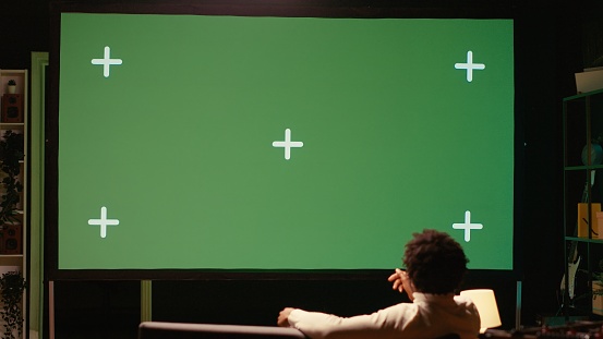 Man using streaming services on ultrawide chroma key TV to binge watch series from the comfort of his apartment. Cord cutter enjoying shows on television set during leisure time on couch